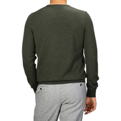 A person is wearing a Green Melange Extra Fine Merino Crew Neck sweater by Gran Sasso and light gray pants. They are standing with their back to the camera.