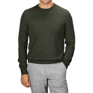 A person wearing a Gran Sasso Green Melange Extra Fine Merino Crew Neck and light gray pants, with hands partially in pockets. The person's face is not visible.