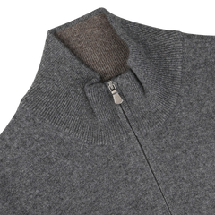 Close-up of the Gran Sasso Grey Melange Cashmere 1/4 Zip Sweater, showcasing its high collar with a partially open zipper that reveals the inner collar lining. Meticulously crafted from pure cashmere, the fabric exudes a soft and textured feel, epitomizing luxurious premium knitwear.