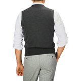 A person is wearing a Gran Sasso Grey Melange Knitted Merino Wool Waistcoat over a white shirt and light gray pants, with their back facing the camera.