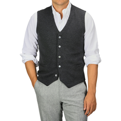 A person wearing a white dress shirt, a Gran Sasso Grey Melange Knitted Merino Wool Waistcoat, and light grey trousers stands with their hands in their pockets.