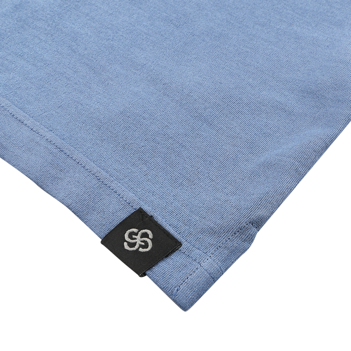 Close-up of the corner of an Indigo Blue Washed Cotton Popover Shirt by Gran Sasso, featuring a black tag with an interlocking double-S logo.