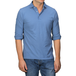 A person wearing a Gran Sasso Indigo Blue Washed Cotton Popover Shirt with rolled-up sleeves and blue jeans stands against a plain background.