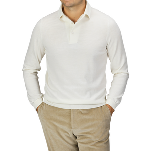 A man wearing a Gran Sasso Ivory Merino Wool One-Piece Collar Polo Shirt with beige corduroy pants, hands in his pockets, stands against a plain background.