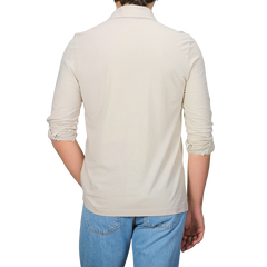 A person, back to the camera, is wearing a slim fit cream long-sleeve shirt that resembles Gran Sasso's Light Beige Washed Cotton Popover Shirt, effortlessly paired with blue jeans.