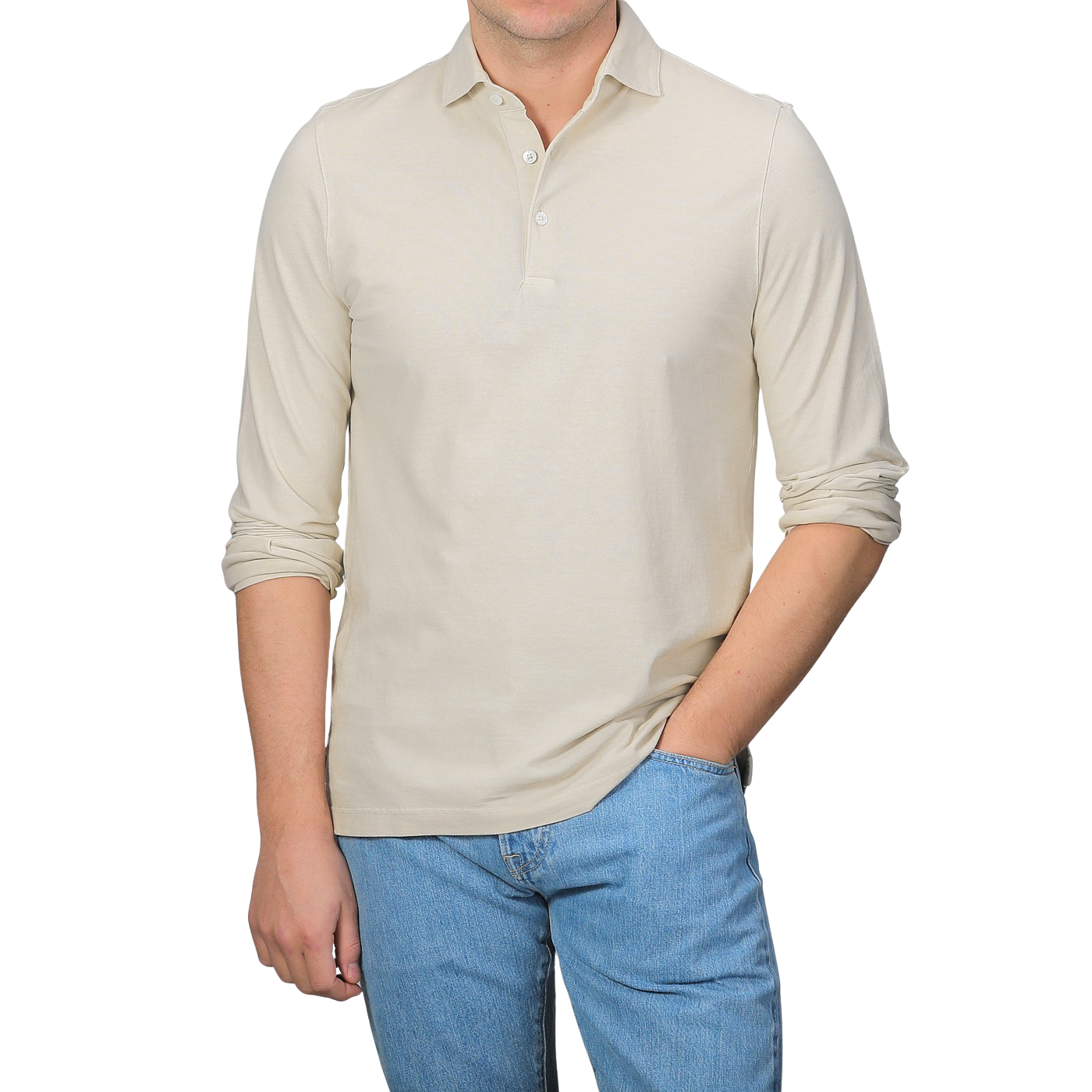 A man in a Gran Sasso Light Beige Washed Cotton Popover Shirt and blue jeans stands with his right hand in his pocket against a plain background.