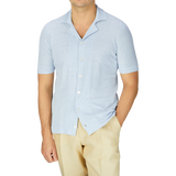 A man in a Gran Sasso light blue linen cotton bowling shirt and tan pants, showcasing his summer wardrobe.