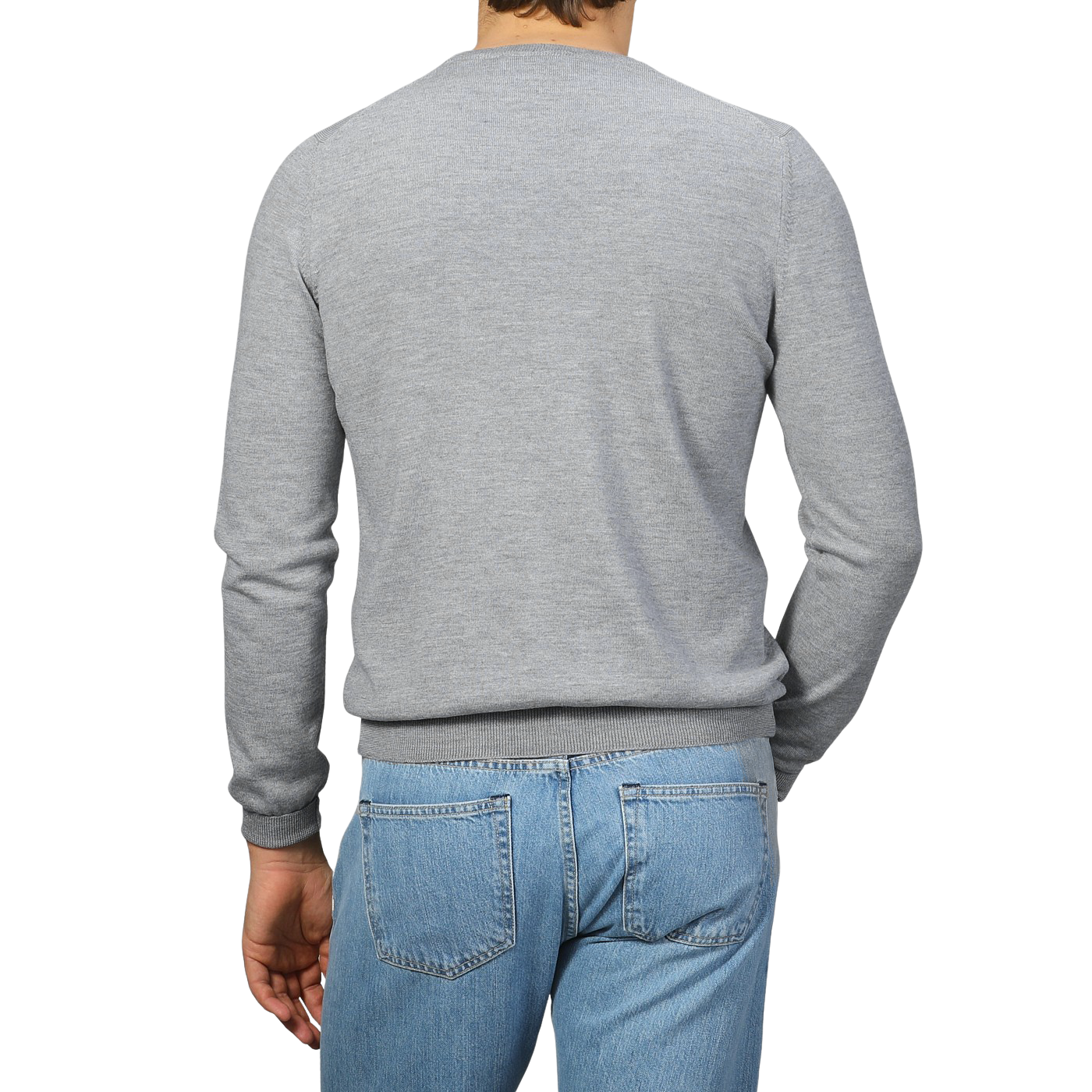 A person in a Light Grey Extra Fine Merino Crew Neck by Gran Sasso and blue jeans stands facing away, highlighting a casual yet polished look.