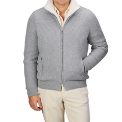 A person wearing a Gran Sasso Light Grey Faux Fur Lined Cashmere Blouson paired with off-white pants stands against a neutral background, with their right hand casually placed in their pocket, embodying the essence of luxury knitwear.