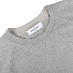 Light grey wool cashmere college sweater featuring a visible white label with the brand "Gran Sasso" and the text "Nido di Larice." This piece of sustainable knitwear is displayed flat on a white surface.