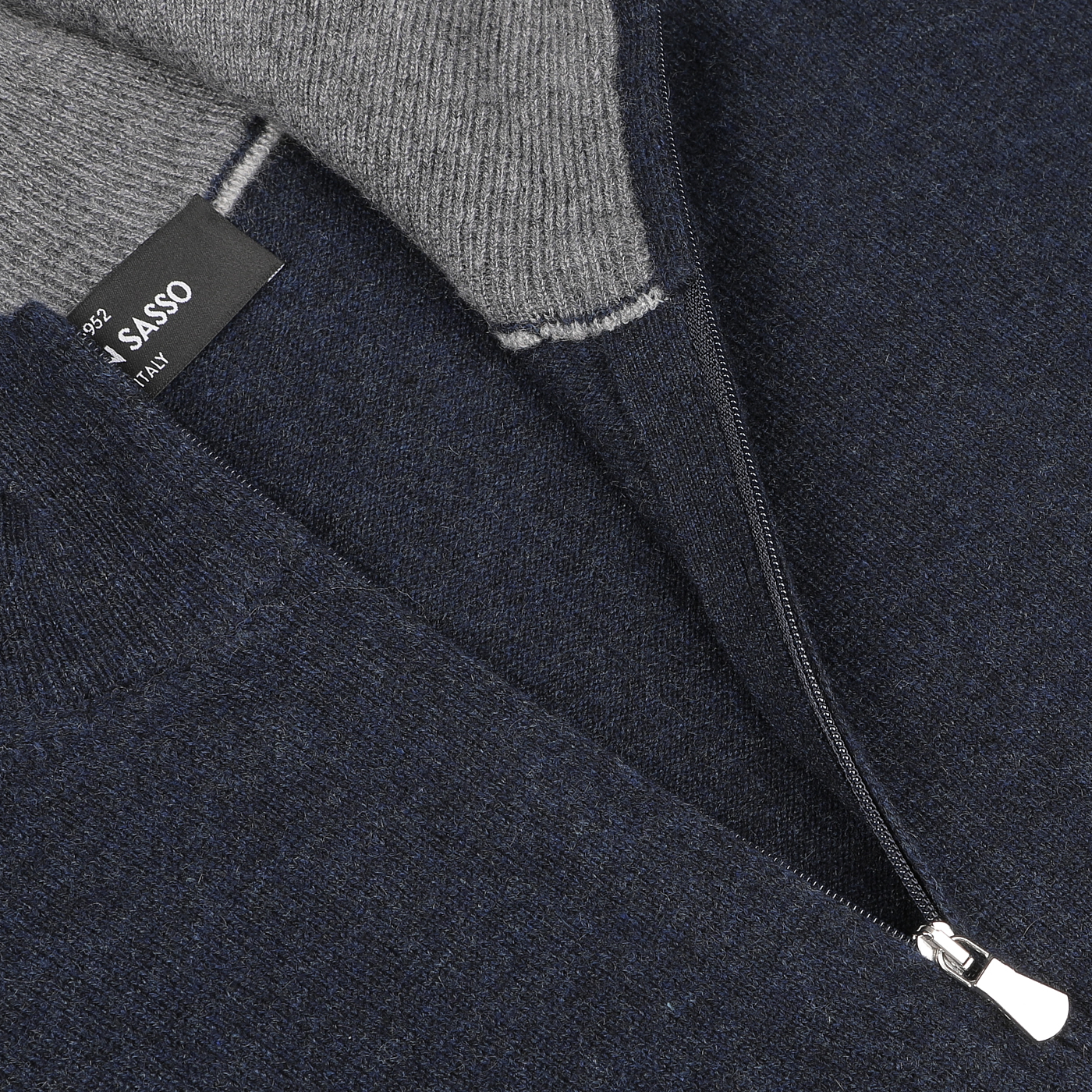 Close-up of a Navy Blue Cashmere 1/4 Zip Sweater by Gran Sasso with a visible brand label inside. The zipper is partially open, revealing the sweater's gray inner lining. This piece epitomizes premium knitwear quality.