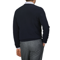 A person is depicted from the back against a plain background, wearing Gran Sasso's Navy Blue Cashmere Crewneck Sweater and gray pants, showcasing the timeless elegance of their knitwear.