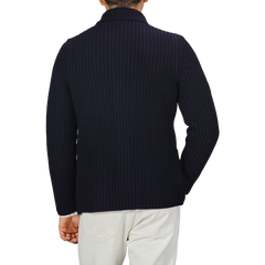 A person wearing a Navy Blue Chunky Knitted Wool Cardigan by Gran Sasso and light-colored pants is shown from the back.