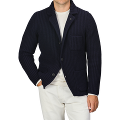 A person wearing a Gran Sasso Navy Blue Chunky Knitted Wool Cardigan over a white shirt and white pants. Their left hand is in their pocket.