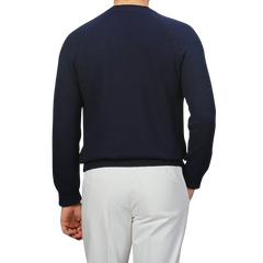 A person faces away against a gray backdrop, wearing a Gran Sasso Navy Blue Cotton Boucle Crewneck Sweater in a regular fit with white pants.