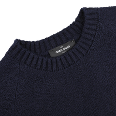 A close-up of the Navy Blue Cotton Boucle Crewneck Sweater from Gran Sasso shows its ribbed neckline. Inside, a black label reads "Gran Sasso, Italy.