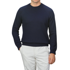 A person in a Gran Sasso Navy Blue Cotton Boucle Crewneck Sweater and white pants stands against a gray background, with the textured fabric adding depth. The person's head is not visible.