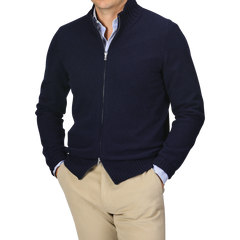 A person wearing a navy blue Felted Cashmere Zip Cardigan by Gran Sasso in a contemporary fit over a light blue shirt and beige pants stands with hands in pockets, facing forward.