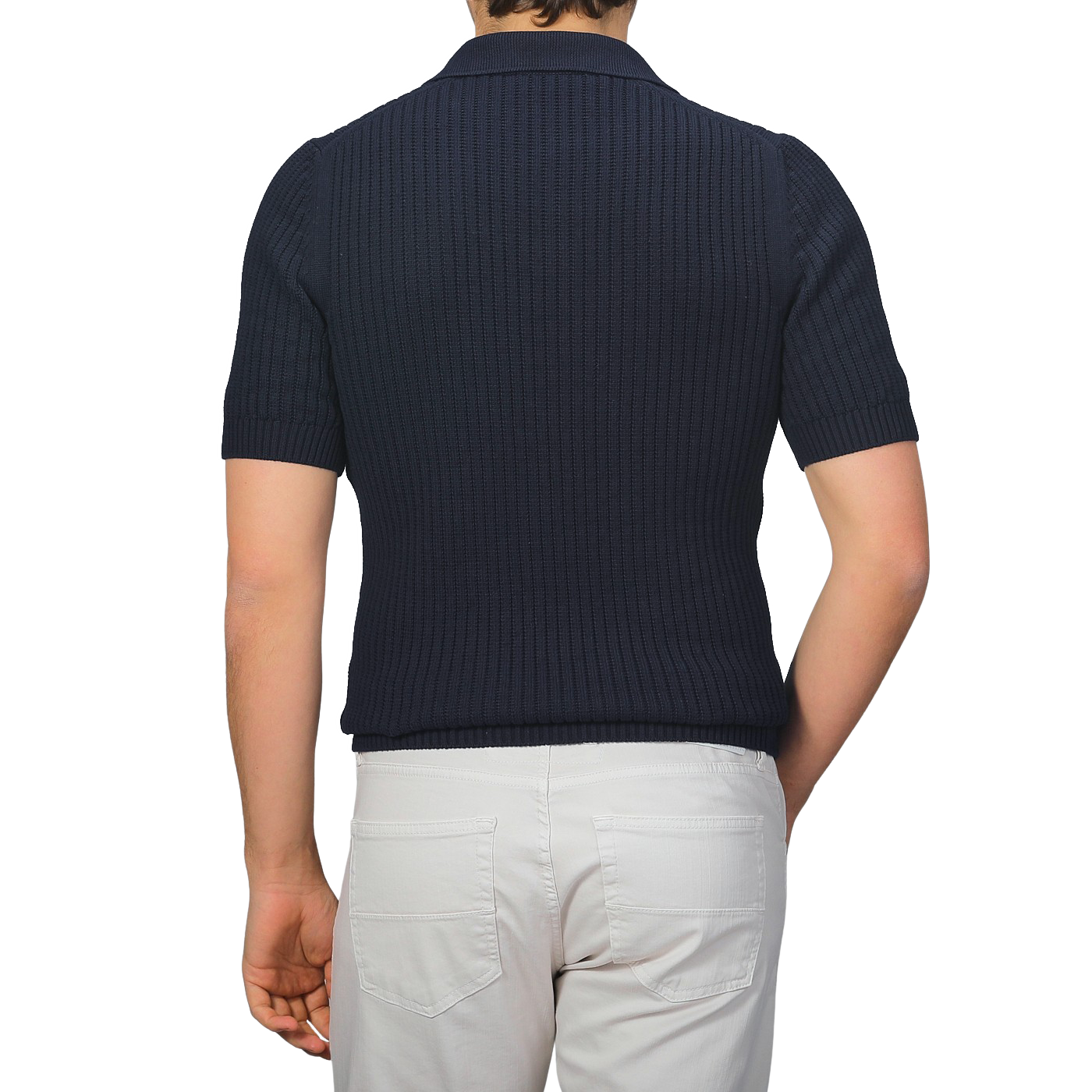 Individual in a navy blue organic cotton polo shirt by Gran Sasso and white pants, seen from behind against a gray background.