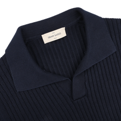 Close-up of a chunky-knit navy blue polo shirt with a collar, labeled "Gran Sasso," made from organic cotton.