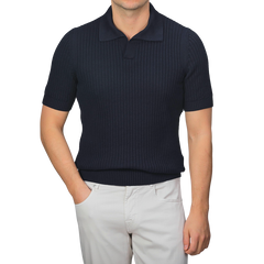 Person wearing a navy blue chunky-knit Gran Sasso polo shirt made of organic cotton and light gray pants against a plain background.