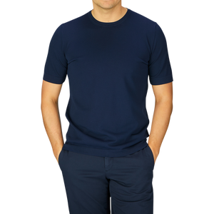Man wearing a Gran Sasso navy blue organic cotton knitted t-shirt and matching pants standing against a grey background.