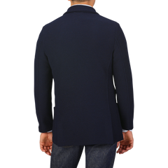 Rear view of a person wearing the Navy Blue Virgin Wool Sartorial Jacket by Gran Sasso, paired with jeans against a plain background.