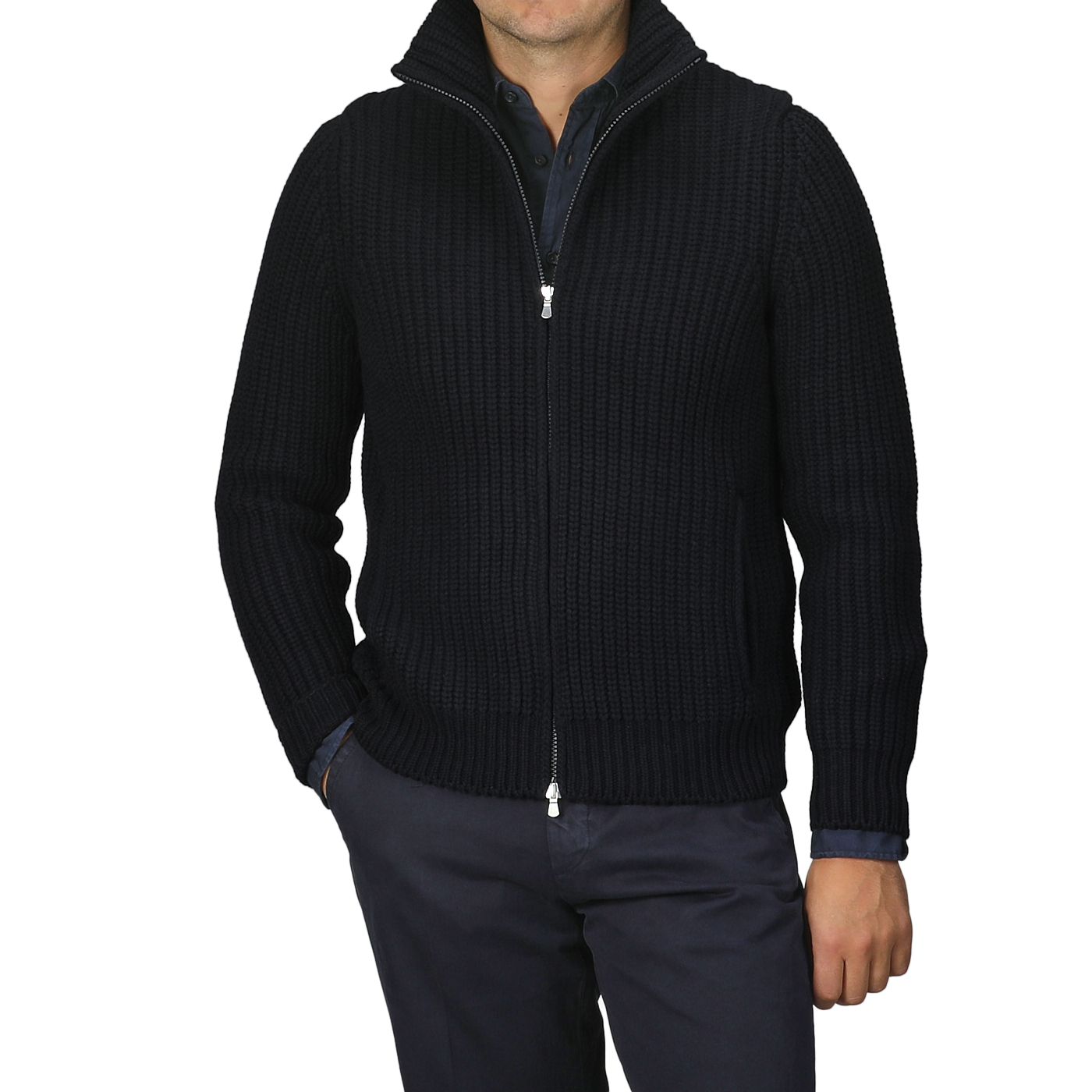 A person wearing a navy blue heavy knit cardigan made of wool and cashmere by Gran Sasso over a dark shirt and pants, with hands in pockets, stands against a plain gray background.