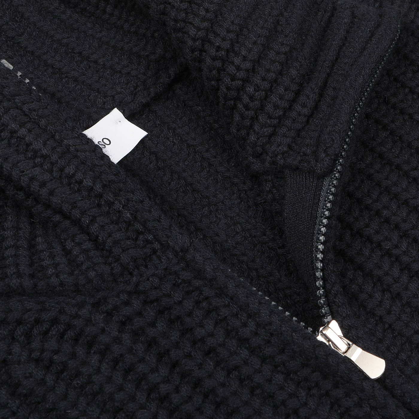 Close-up of a navy blue wool cashmere heavy knit cardigan, highlighting the zipper and a small visible tag inside, reminiscent of Gran Sasso's fine knitwear.