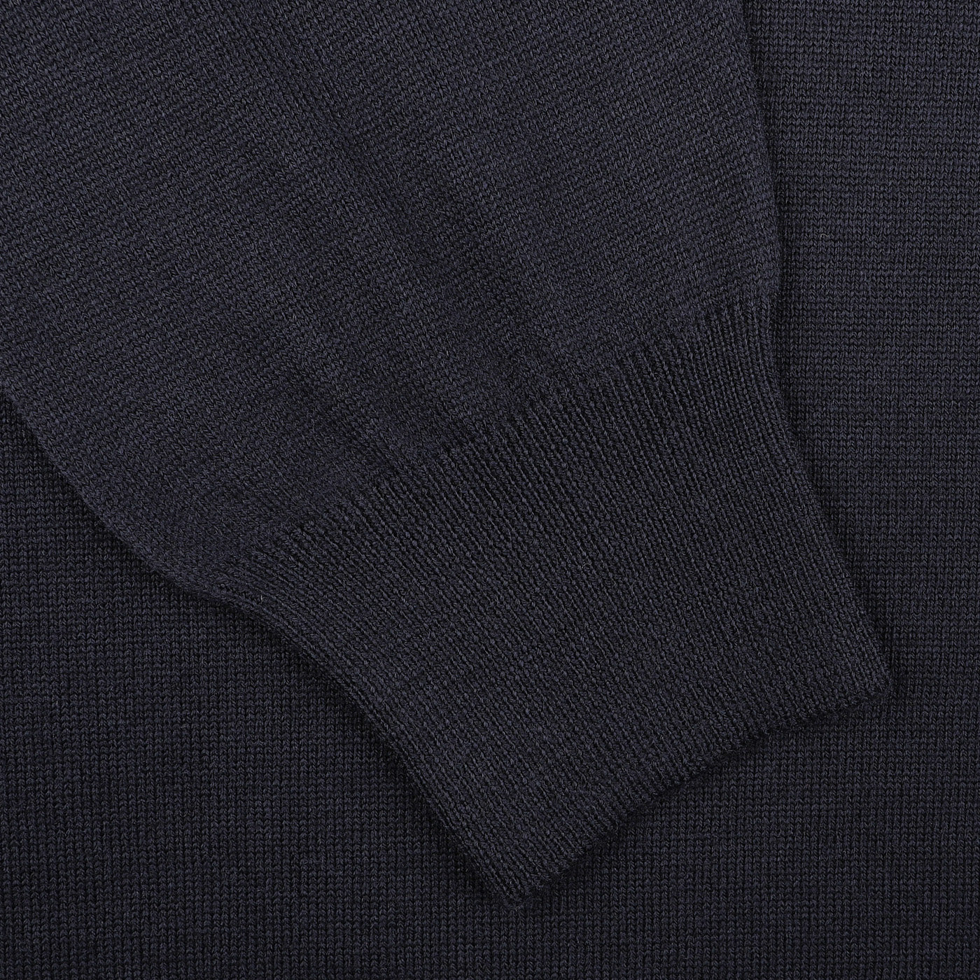 A close-up of Gran Sasso's Navy Extra Fine Merino Crew Neck fabric exuding warmth, showcasing a sleeve cuff folded neatly on top—an ideal wardrobe addition.