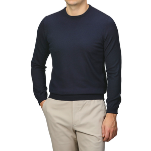 A person wearing a Gran Sasso Navy Extra Fine Merino Crew Neck and beige pants stands against a gray background, offering a touch of comfort and warmth to any wardrobe.