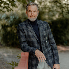 A man in a Gran Sasso Navy Extra Fine Merino Roll Neck jacket leaning against a railing.