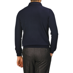 A person wearing a Navy Merino Wool One-Piece Collar Polo Shirt by Gran Sasso and gray pants is standing with their back to the camera.