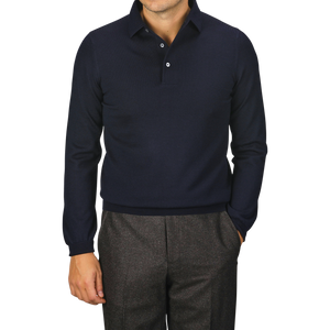 A person wearing a Navy Merino Wool One-Piece Collar Polo Shirt by Gran Sasso and brown trousers stands with one hand in their pocket.