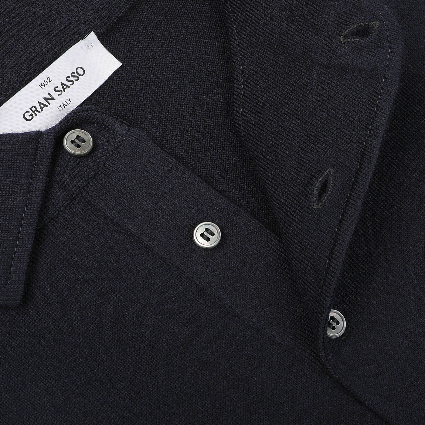 Close-up of a Navy Merino Wool One-Piece Collar Polo Shirt by Gran Sasso, showcasing buttons and a visible clothing label inside; this extra-fine merino wool piece is akin to a luxurious dark-colored sweater with a collar.