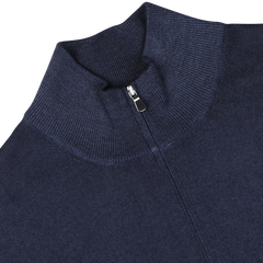 Close-up of the Gran Sasso Navy Vintage Merino Wool Zip Cardigan featuring a half-zip collar and silver zipper detail. Crafted from pure merino wool, the knit fabric boasts a ribbed texture, giving it a vintage feel. The sweater is laid flat on a gray background.