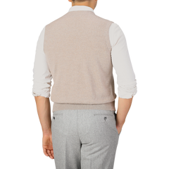 A person wearing a Gran Sasso Oatmeal Beige Knitted Merino Wool Waistcoat over a white shirt and light gray pants is shown from the back.