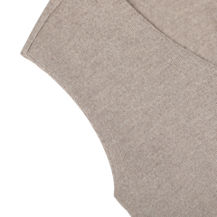 Close-up of a light brown textured merino wool fabric with visible stitching, showcasing the intricate detail of a corner and curved edge from a Gran Sasso Oatmeal Beige Knitted Merino Wool Waistcoat.