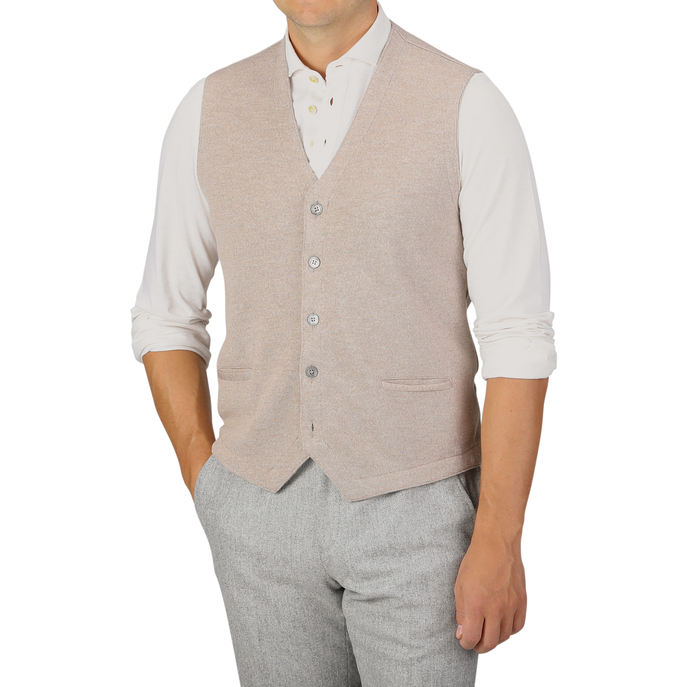 A person wearing a Gran Sasso Oatmeal Beige Knitted Merino Wool Waistcoat over a white long-sleeve shirt with rolled-up sleeves and light gray pants.