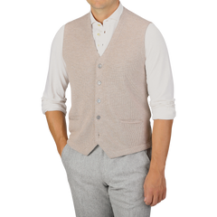 A person wearing a Gran Sasso Oatmeal Beige Knitted Merino Wool Waistcoat over a white long-sleeve shirt with rolled-up sleeves and light gray pants.