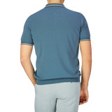 Man standing with his back to the camera, wearing a Gran Sasso Ocean Blue Fresh Cotton Polo Shirt with a Capri collar and light grey trousers.