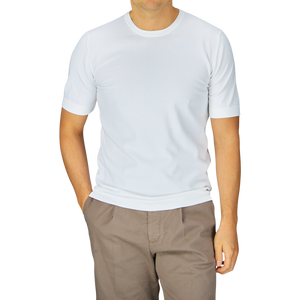 Man in a Gran Sasso Off-White Organic Cotton T-shirt and brown pants standing against a grey background.