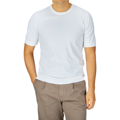 Man in a Gran Sasso Off-White Organic Cotton T-shirt and brown pants standing against a grey background.