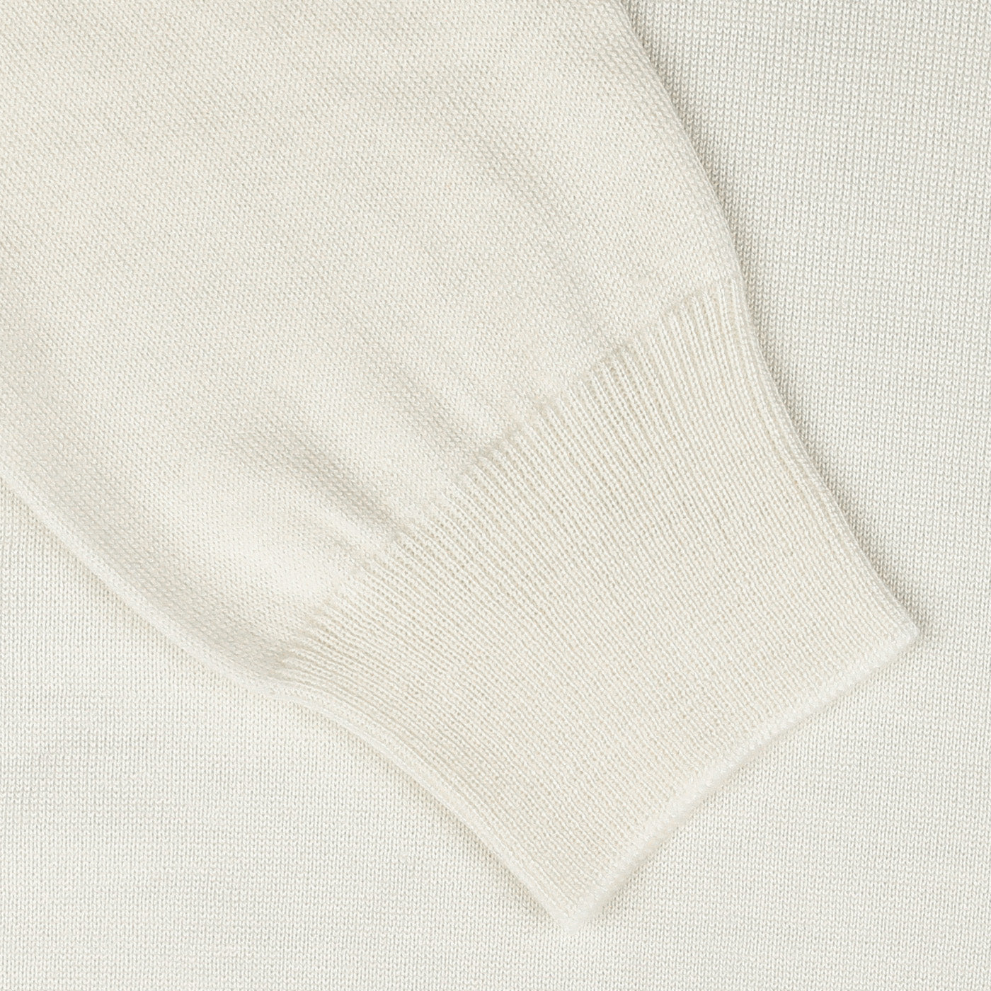 Close-up of a white knitted fabric, showing the sleeve cuff of the Gran Sasso Off White Extra Fine Merino Roll Neck sweater with ribbed detailing and a slightly textured weave.