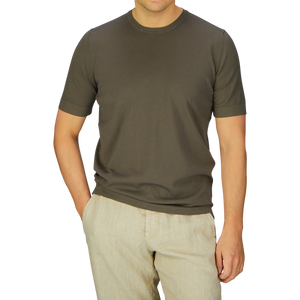 Man wearing a Gran Sasso Olive Green Organic Cotton T-shirt and beige pants standing against a blue background.