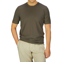 Man wearing a Gran Sasso Olive Green Organic Cotton T-shirt and beige pants standing against a blue background.