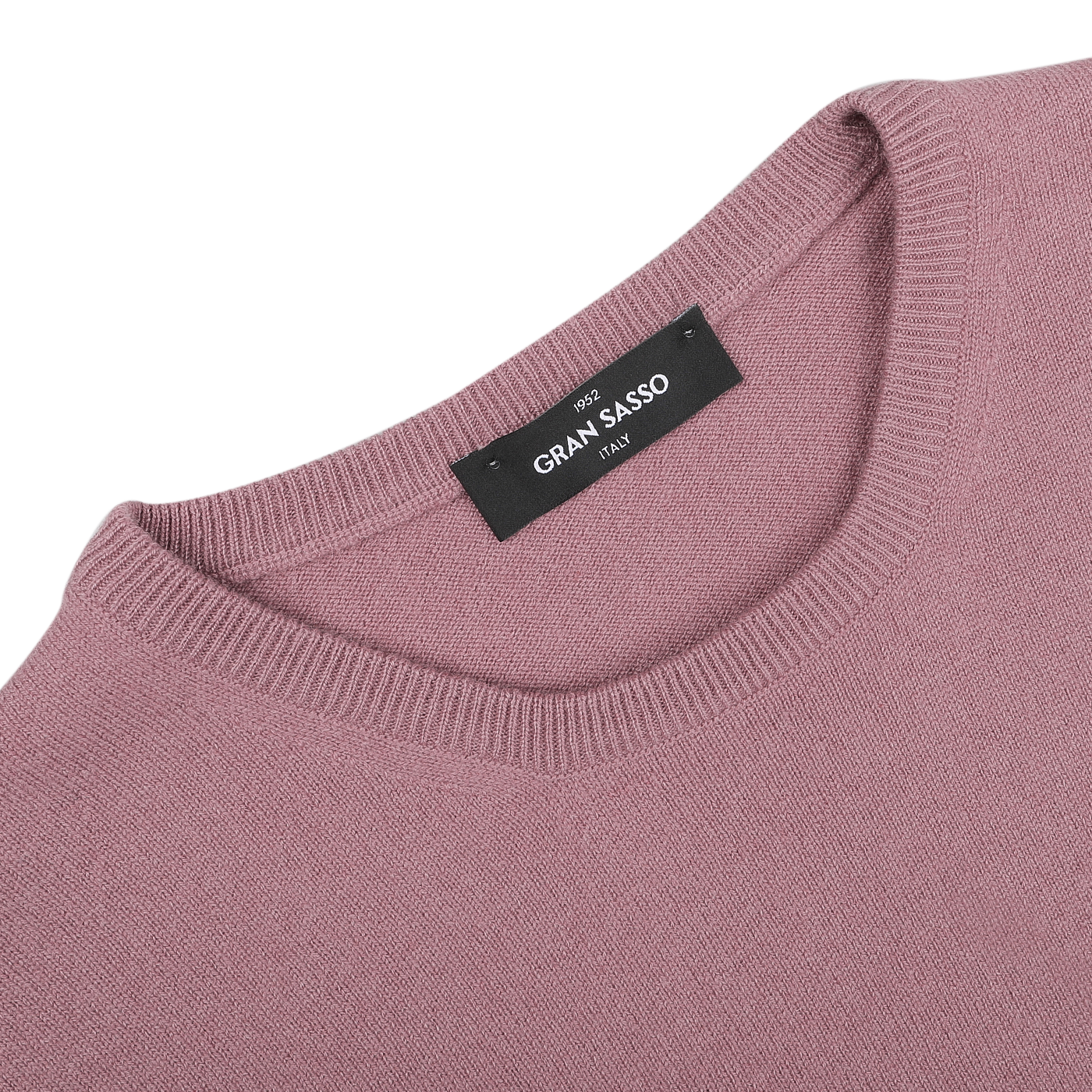 A close-up of a folded Pale Pink Cashmere Crewneck Sweater highlights its luxurious texture. The black label features "Gran Sasso" in white text, emphasizing the brand's commitment to sustainable knitwear.