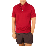 A man wearing a Gran Sasso Raspberry Red Cotton Filo Scozia polo shirt and shorts.