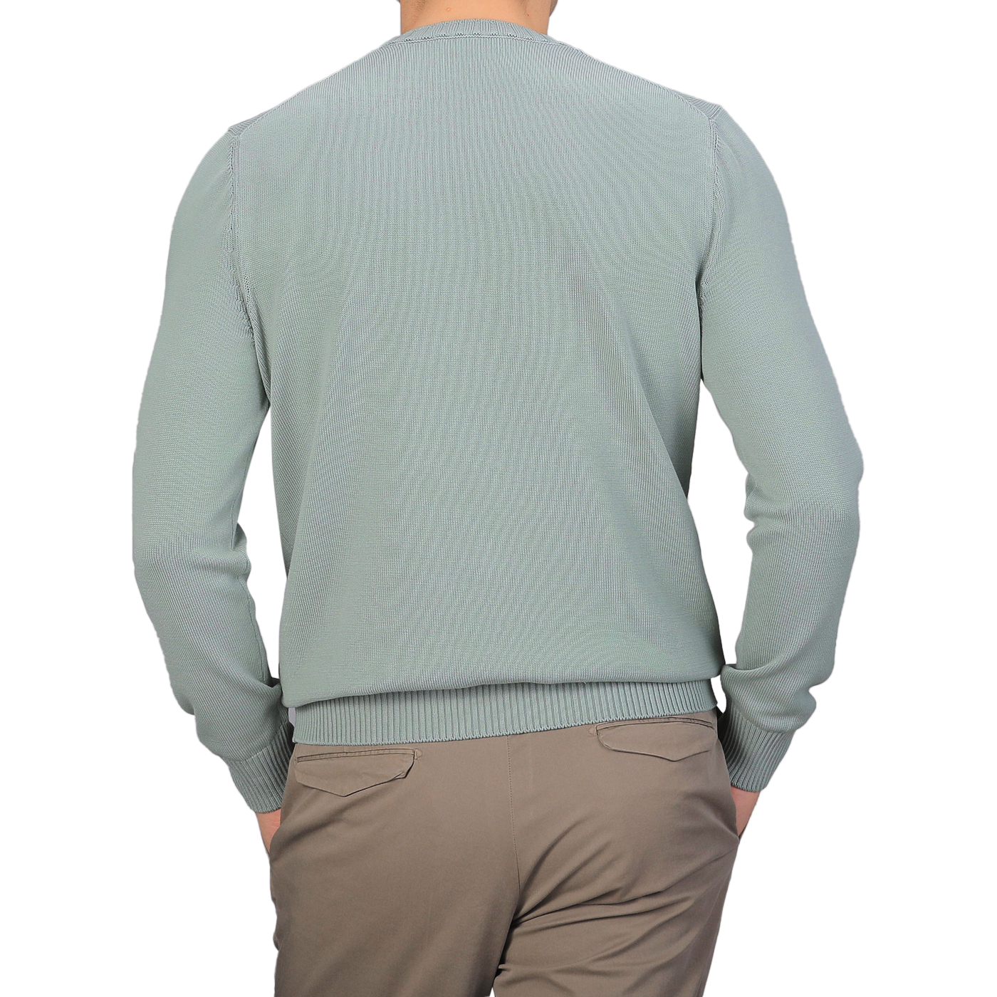 An individual is facing away from the camera against a gray background, wearing a Sage Green Egyptian Cotton Crewneck Sweater by Gran Sasso paired with beige pants.