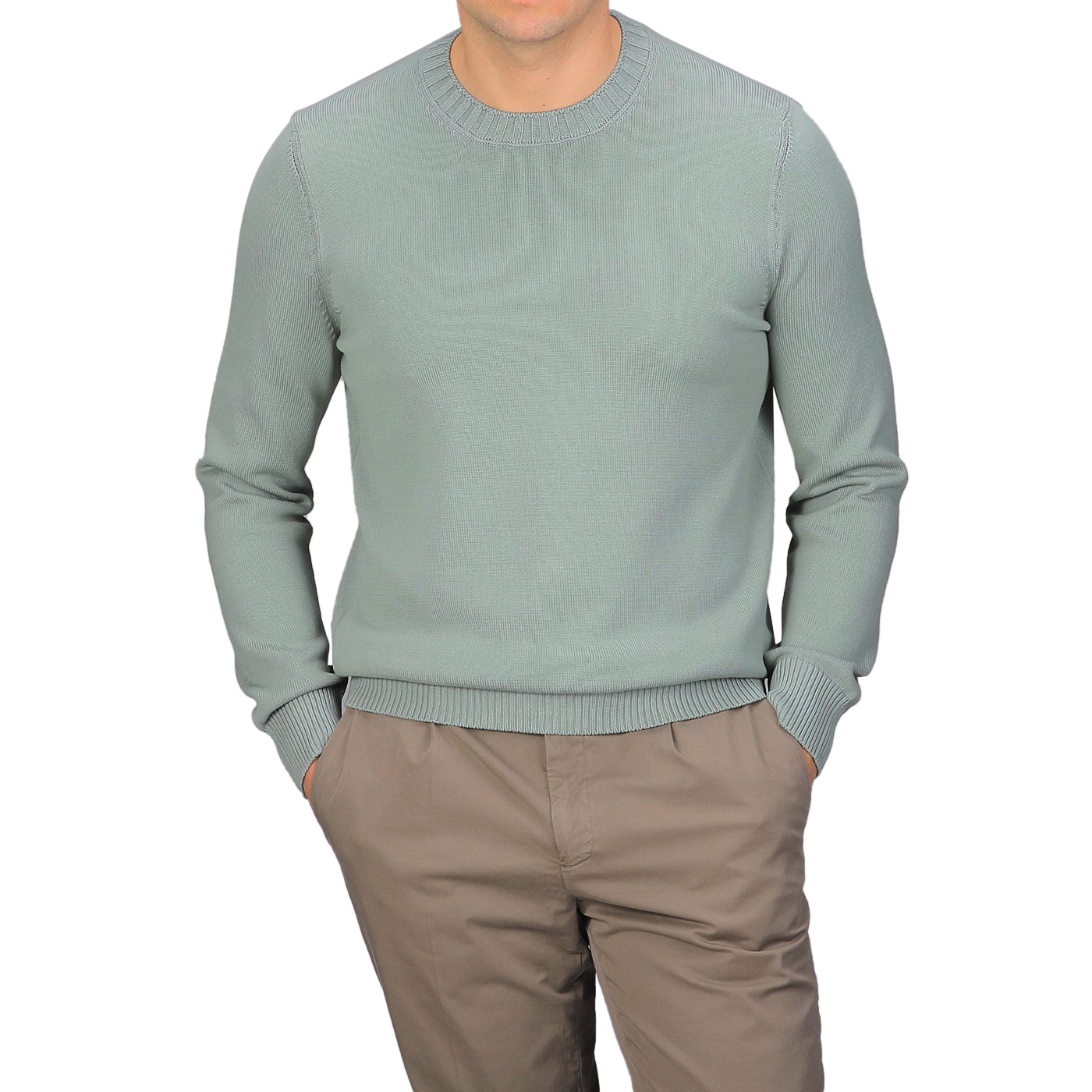 A person wears a Sage Green Egyptian Cotton Crewneck Sweater by Gran Sasso with beige pants, hands in pockets against a plain gray background.